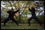 Aka-chan swings the naginata around and strikes at Kubo-chan's wrist.