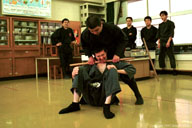 Yoshida-san choking Kuwata-san with a hanbo.